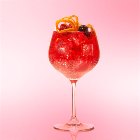 Do'Mo Scrumptious Berry Bramble served in a balloon glass with lemon rind garnish and fresh fruit.
